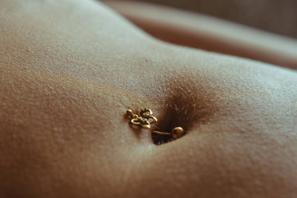 mooie vrouwelijke buik. piercing van de navel - Foto, afbeelding