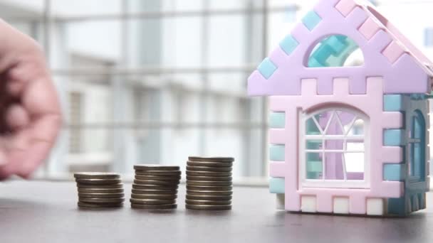 a házfinanszírozás koncepciója egy halom érmével és egy ház az asztalon  - Felvétel, videó