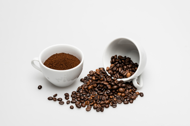 gemahlener Kaffee und Bohnen in der Nähe von Tassen auf weiß - Foto, Bild