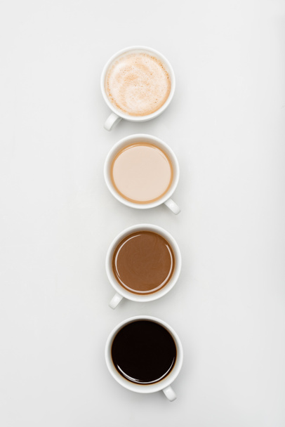 vrchní pohled na různé čerstvé kávové nápoje s mlékem na bílém - Fotografie, Obrázek