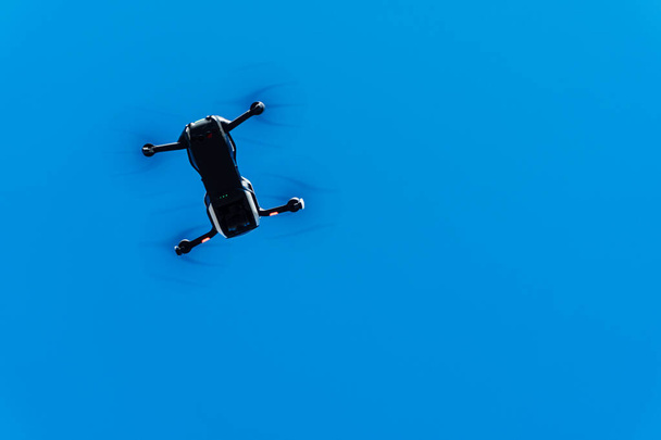 Общее изображение белого дрона, летящего по голубому небу. Оборудование дистанционного управления для воздушного наблюдения. - Фото, изображение