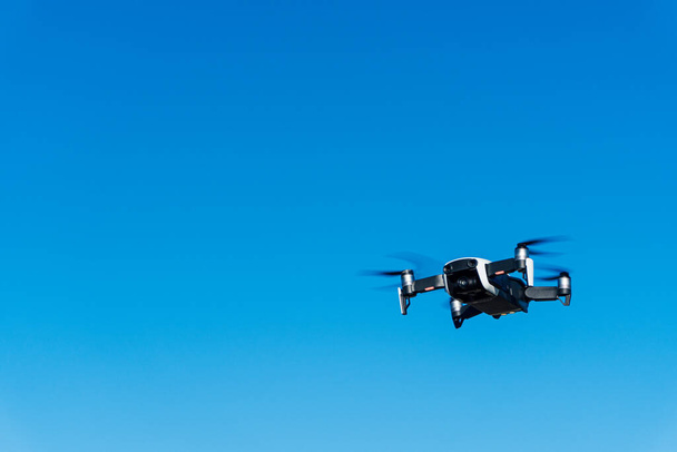 Generisches Bild einer weißen Drohne, die über einen blauen Himmel fliegt. Geräte zur Fernsteuerung für die Luftüberwachung. - Foto, Bild