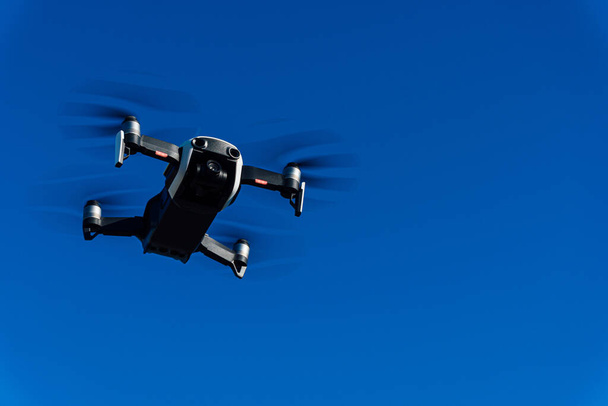 Generic image of a white drone flying across a blue sky. Remote control equipment for aerial surveillance. - Photo, Image