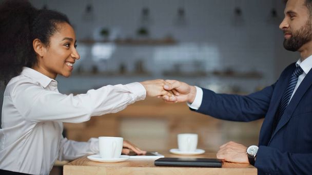 カフェでの朝のミーティング中に握手をする幸せな異人種間のビジネスパートナーの - 写真・画像