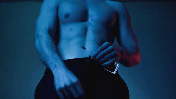 partial view of sexy and muscular man undressing on blue - Photo, Image