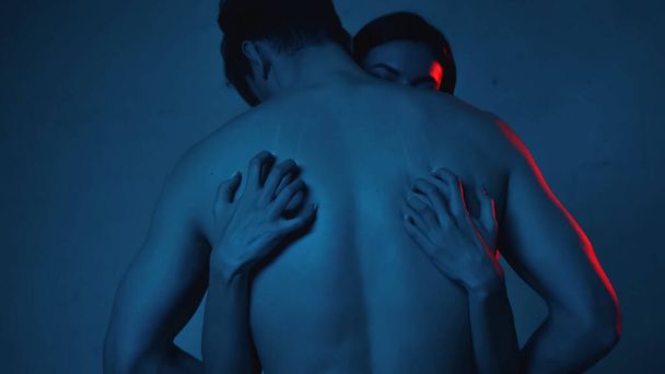 brunette woman scratching back of shirtless man on blue - Foto, afbeelding
