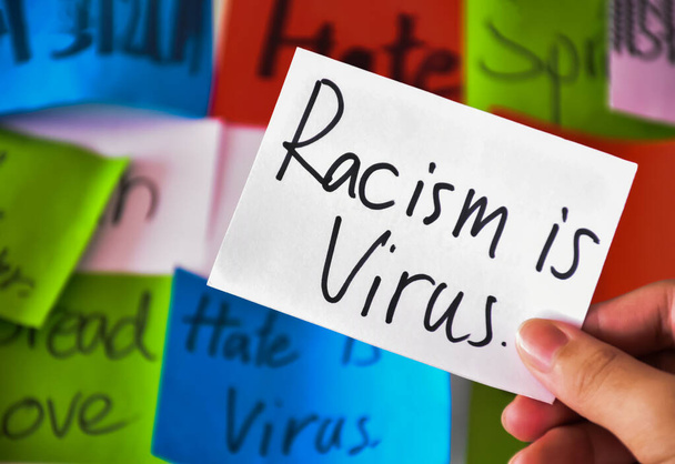 Woordkaart 'Racisme is virus.' in de hand houden van een concept om de internationale gemeenschap op te roepen te stoppen met het haten, kwetsen en lastigvallen van Aziatische mensen in de verspreiding van de covid-19-crisis. - Foto, afbeelding