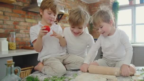Vrolijke Kaukasische jongens met blond haar pizza maken in een puinhoop zonder ouders. - Video