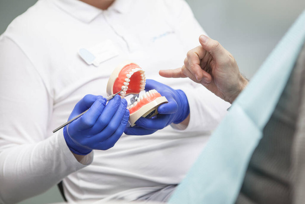 Μη αναγνωρίσιμος οδοντίατρος και ο ασθενής του συζητούν για οδοντιατρική περίθαλψη, οδοντιατρικές οδοντοστοιχίες - Φωτογραφία, εικόνα