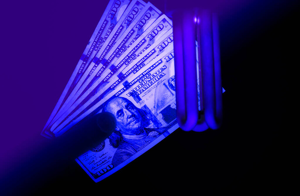 Vervalst geld controleren met ultraviolette lamp. Fraudebestrijding. - Foto, afbeelding