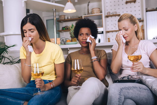 Три друзі-жінки дивитися сумний фільм вдома в дивані, що плаче, торкаючись
. - Фото, зображення