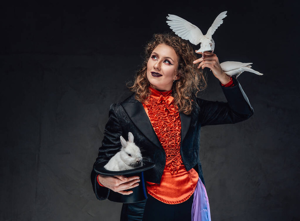 Bruin harige vrouwelijke artiest met een konijn en twee duiven in donkere achtergrond - Foto, afbeelding
