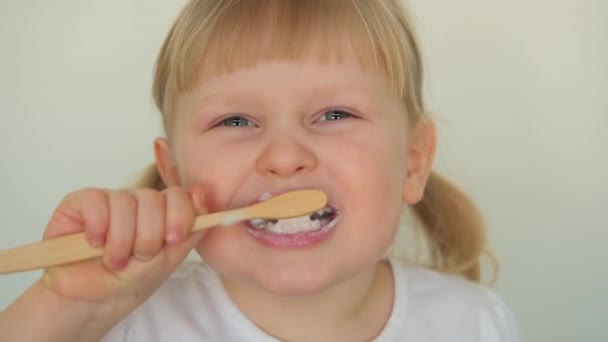 Fecha. Pequena menina criança loira rindo e diligentemente escova os dentes com pasta de dentes. - Filmagem, Vídeo