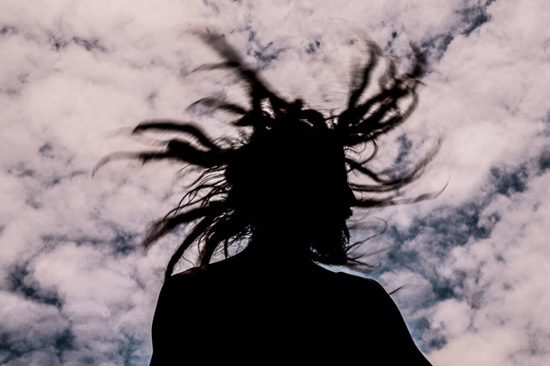 Uomo che muove i capelli con dreadlocks con cielo blu e nuvole sullo sfondo - Foto, immagini