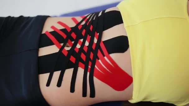 Crossed kinesio tape on the abdomen of young girl. Kinesiology tape on girl belly. Sport tratment. - Footage, Video