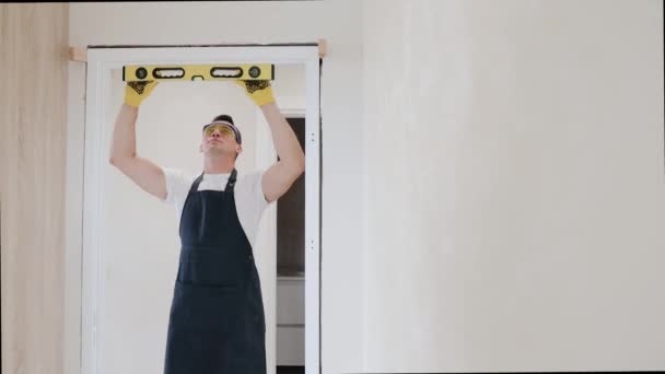 Male carpenter at interior wood door installation working with spirit level. Waterpas is an instrument for measuring horizontal and vertical level of surfaces - Footage, Video