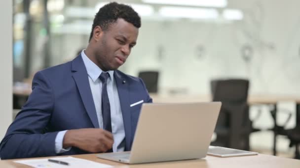 Empresario africano que tiene dolor de espalda mientras usa el ordenador portátil  - Imágenes, Vídeo