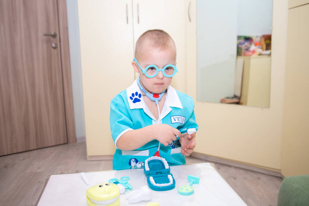 Хлопчик з синдромом Дауна грає як лікар, дитина в костюмі лікаря, діти з обмеженими можливостями
. - Фото, зображення