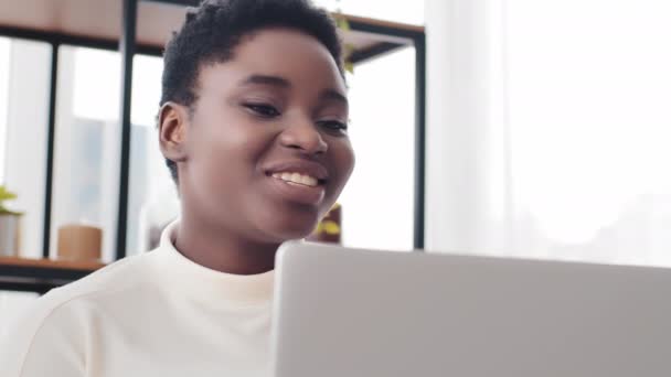 Evden bilgisayarla uzaktan kumandalı internet görüntülü konuşma yapan Afrikalı Amerikalı serbest çalışan bir öğretmenin portresi. Afro siyah kadın el sallıyor. Merhaba diyor. Görüntülü konuşma konferansında konuşuyor. - Video, Çekim