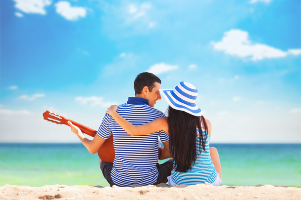 Young couple with guitar on the beach in summer day - Photo, Image