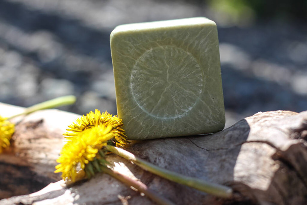 Green natural face soap on the tree branch with yellow flowers on sunny day - Photo, Image