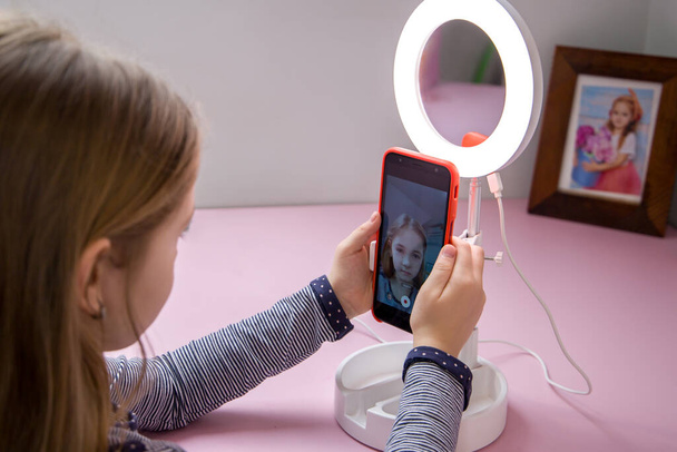 Een klein meisje speelt met een blogger kit die een ring licht bevat. - Foto, afbeelding