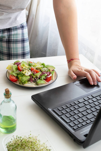 Uma mulher fez uma salada vegetariana verde usando uma receita da internet. Conceito de cozinha online. Orientação vertical. - Foto, Imagem