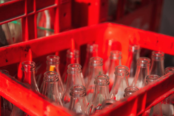 Az üvegek egy piros műanyag dobozban vannak. Üres üvegek nyaka. Üvegtartályok szénsavas italok alatt - Fotó, kép