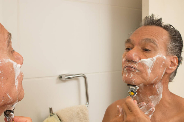 Старший чоловік у ванній з кремом для гоління на обличчі гоління
 - Фото, зображення