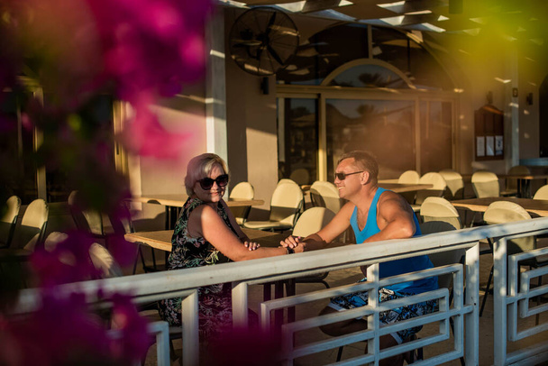 Igazi emberek házaspár ül a szabadtéri kávézóban waring napszemüveg. - Fotó, kép
