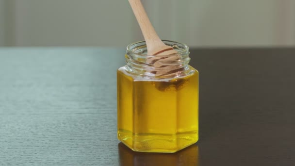 Miele grezzo organico liquido in vaso di vetro con paletta di legno. - Filmati, video