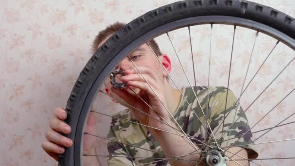 El tipo repara la rueda de la bicicleta, aprieta los rayos al volante. Concepto de reparación de bicicletas - Imágenes, Vídeo