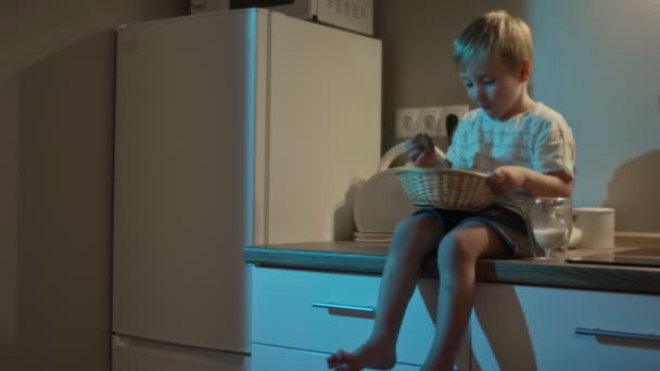 Kleine jongen zit op keukentafel en eet 's nachts koekje - Video