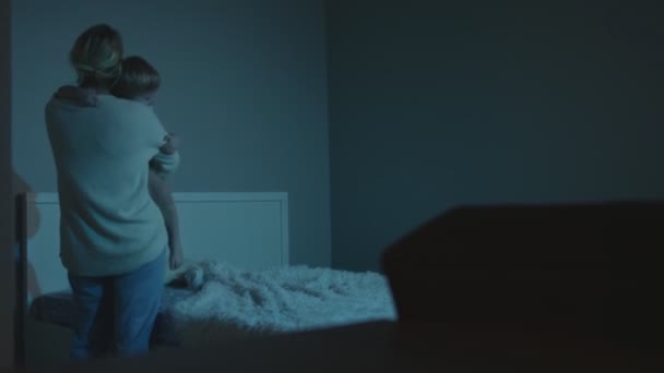 Äiti laittaa lapsen sänkyyn suukkoja pää ennen nukkumaanmenoa - Materiaali, video