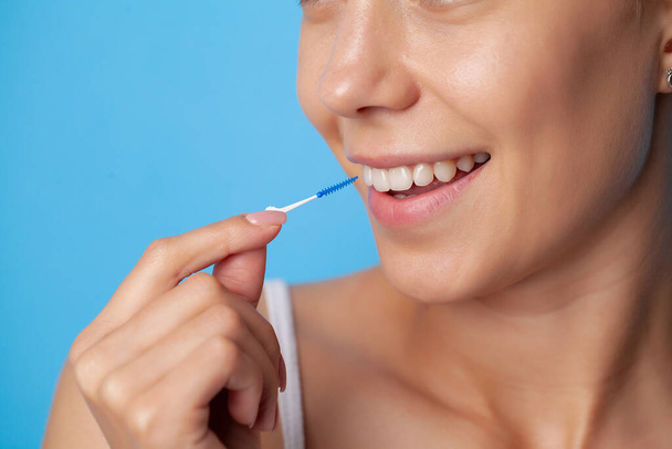 女性は歯間空間をきれいにするためにブラシを使用します - 写真・画像
