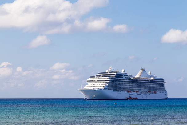 Большой роскошный красивый круизный лайнер на карибском море, на фоне голубого неба и белых облаков. - Фото, изображение