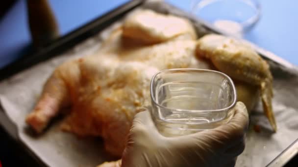 調理される準備ができて、ベテランの大きいspchocked生の鶏とベーキングトレイに水のガラスを注ぐ女性シェフ。shkmeruli料理のプロセス-グルジア料理 - 映像、動画