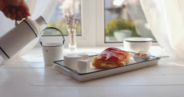 Desayuno saludable por la mañana con leche, croissant recién horneado y vista desde la ventana, video en cámara lenta de 4k - Imágenes, Vídeo