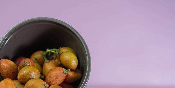 ピンク色の背景にナチュラのカフェラナフルーツ(Bunchosia armeniaca) 。ブラジル原産の植物。薬用木の果実、エキゾチックな果物。大西洋の森の原生植物。珍しい食品工場 - 写真・画像