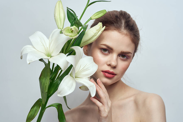 femme avec des fleurs blanches sur fond gris portrait gros plan mode maquillage - Photo, image