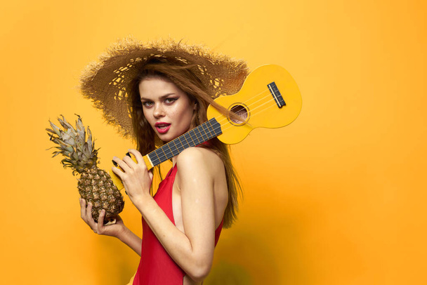 Cheerful woman in red ukulele t-shirt Exotic fruit yellow background lifestyle - Zdjęcie, obraz