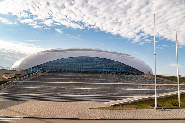 der Bolschoi-Eispalast im Olympiapark Sotschi an einem sonnigen Tag mit Blick auf die große Treppe und den Himmel mit schönen Wolken. - Foto, Bild