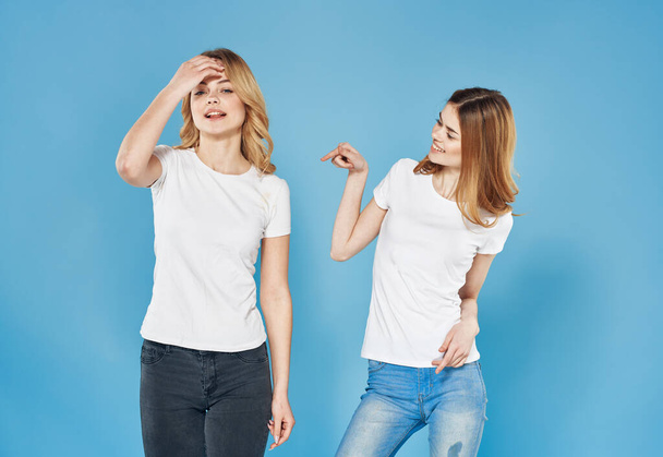 two girlfriends in white t-shirts friendship emotions blue background - Foto, Imagem