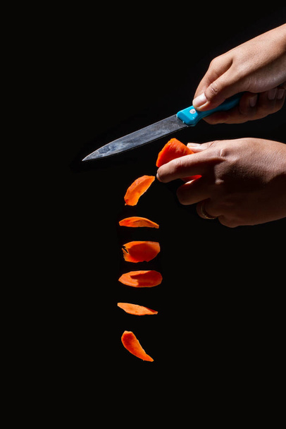 Hombre sosteniendo un cuchillo cortó zanahorias en pedazos. - Foto, Imagen