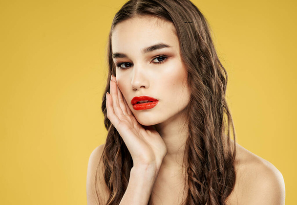 Brunette woman with red lips on a yellow background and makeup with eyeshadow - Photo, Image