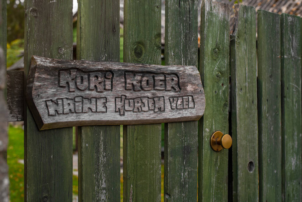 Vicces jel: "Óvakodj a kutyától. Félj jobban a feleségedtől ". észt nyelven, fából készült kerítésen. - Fotó, kép