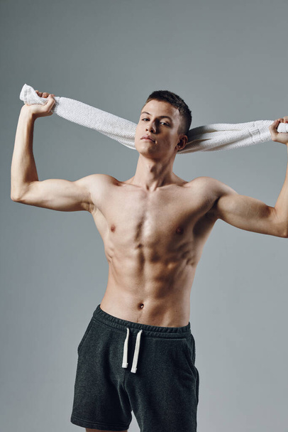 homme tenant des serviettes derrière sa tête aspect athlétique gymnase d'entraînement - Photo, image