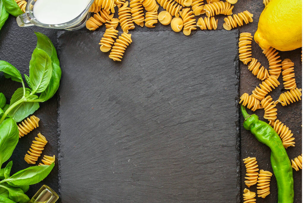 bovenaanzicht op ingrediënten voor pasta op donkere achtergrond - Foto, afbeelding