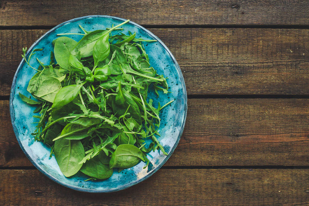fresh green spinach leaves in a bowl on a wooden background. top view. - Valokuva, kuva