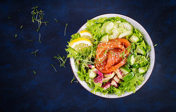 Кетогенный диетический завтрак. Salt salmon salad with greens, cucumbers, celery and armelon radish. Кето, палео-ланч. Вид сверху, выше - Фото, изображение